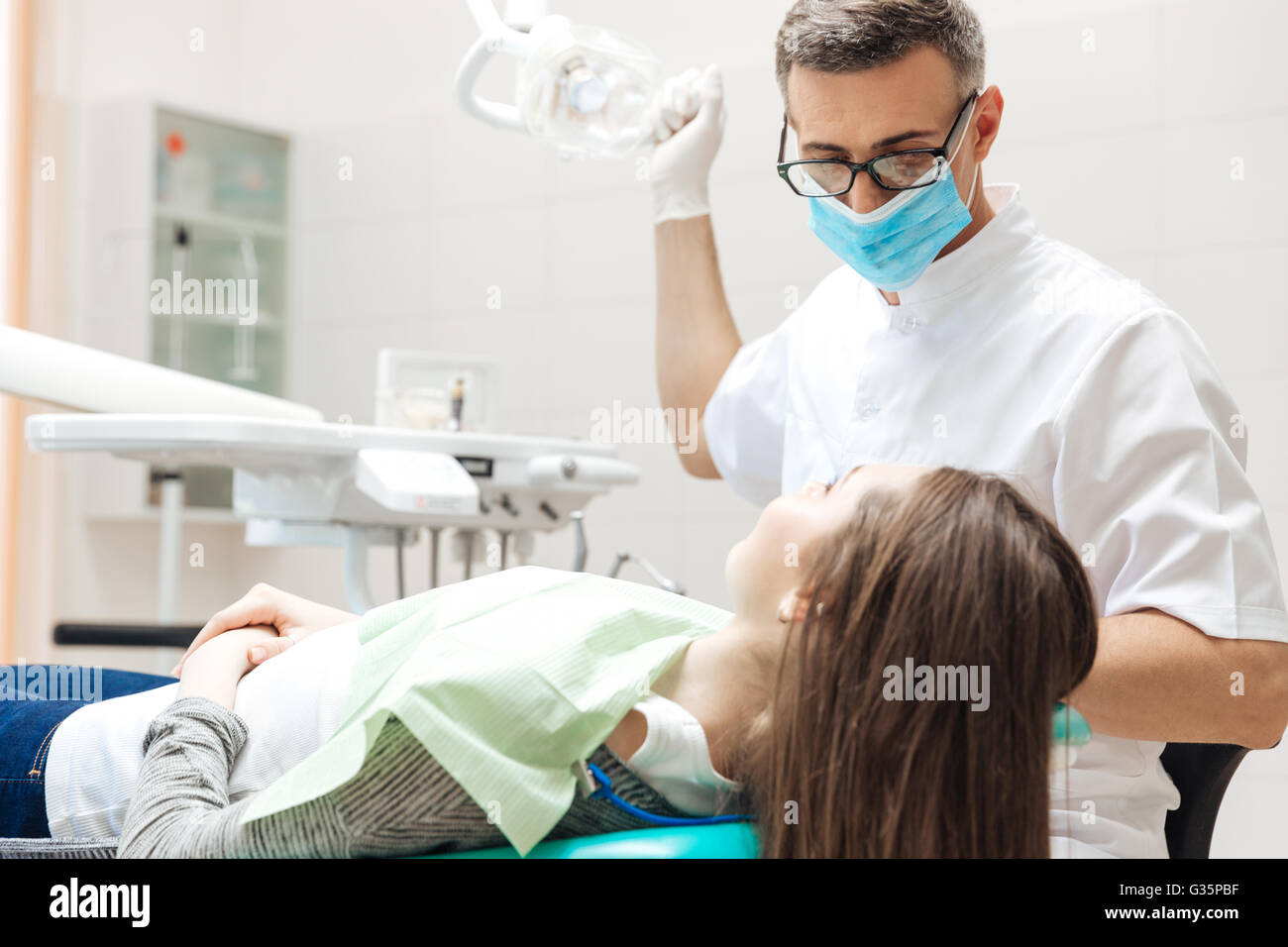 Dentista molto attentamente verificare e riparare il dente del suo giovane paziente di sesso femminile in clinica Foto Stock