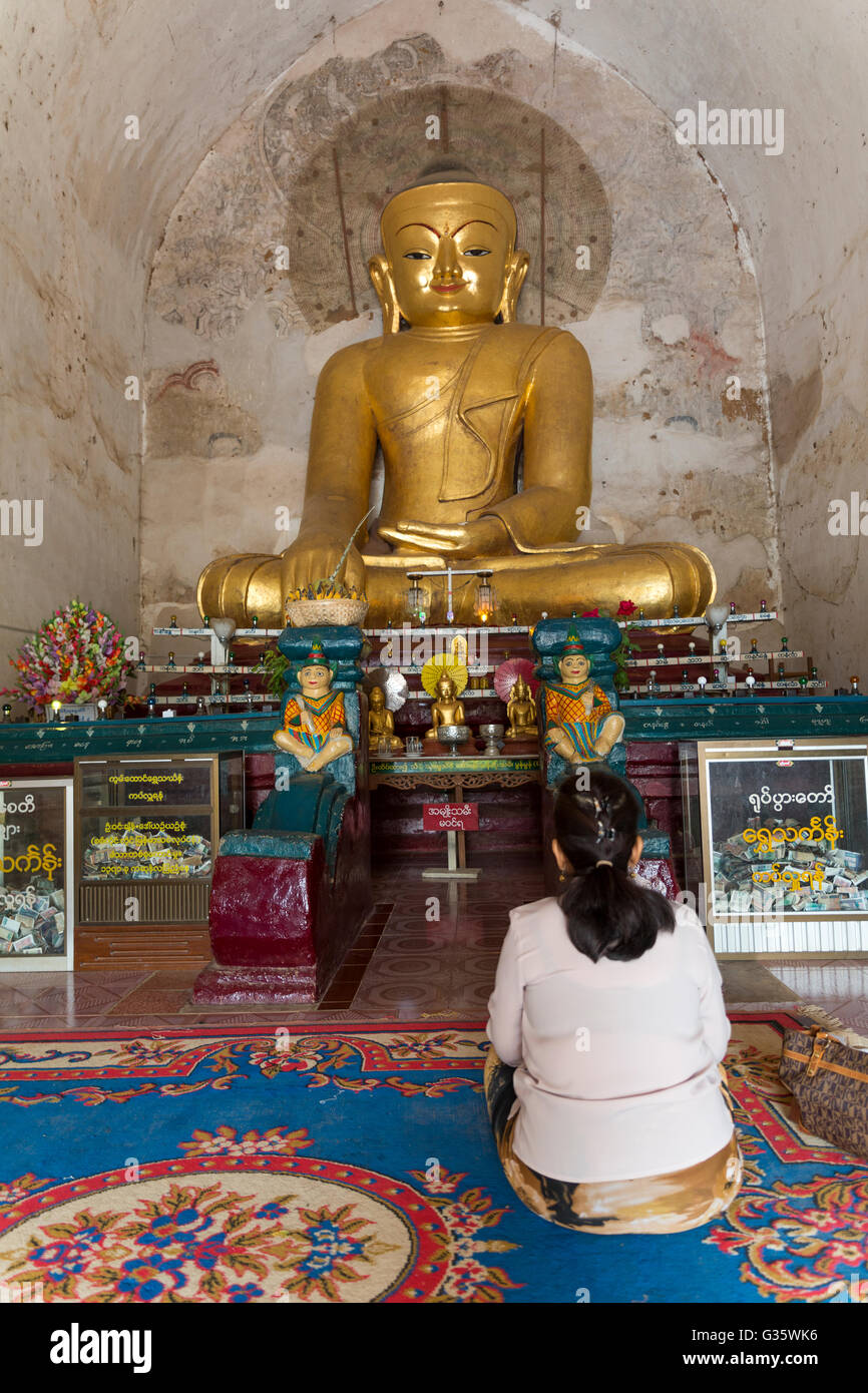 Donna facendo leva sulla parte anteriore di un ornato statua di Buddha nel tempio, il vecchio tempio di architettura, Myanmar, Birmania, Asia del Sud, Asia Foto Stock