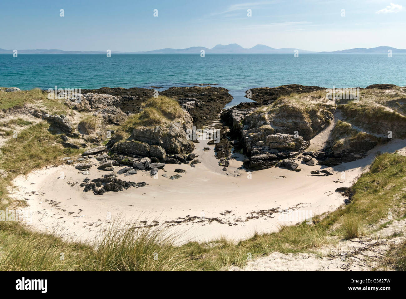 Piccola insenatura di sabbia sulla isola di Colonsay con isola di Jura in distanza, scozzesi Ebridi, Scotland, Regno Unito. Foto Stock