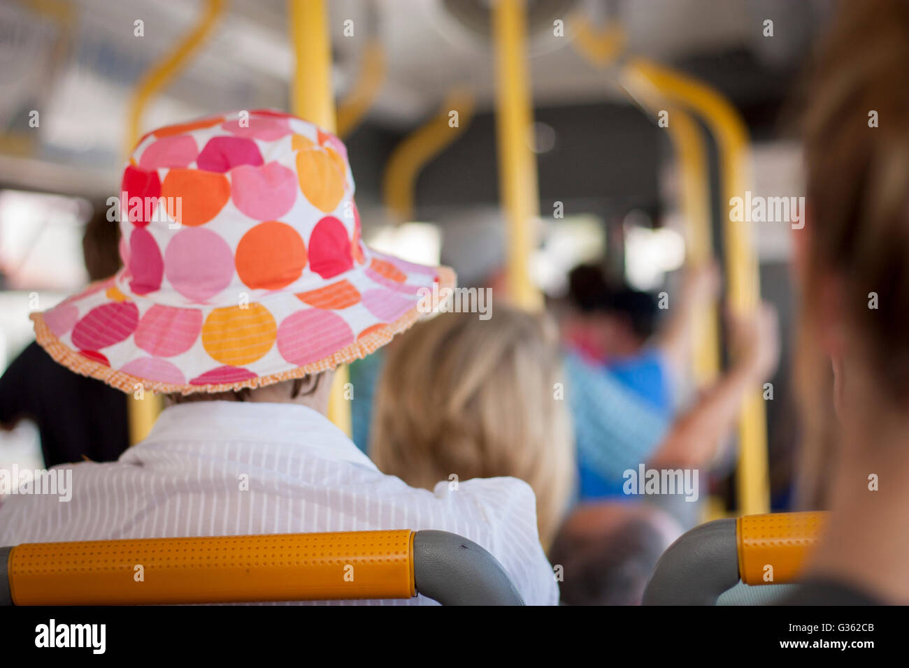 Signora che indossa una colorata estate hat su un bus Foto Stock