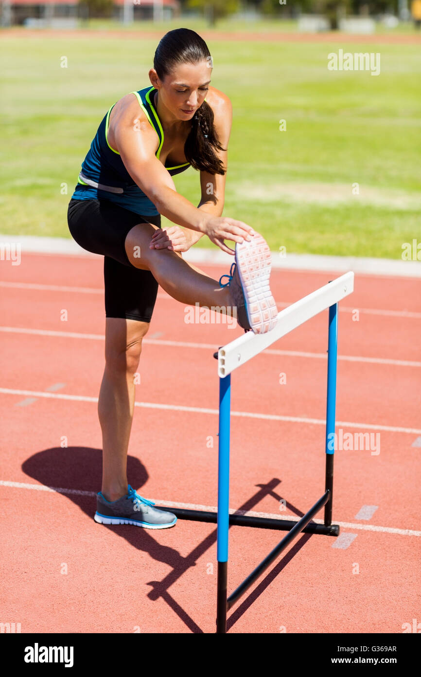 Atleta femminile in fase di riscaldamento al di sopra di ostacolo Foto Stock