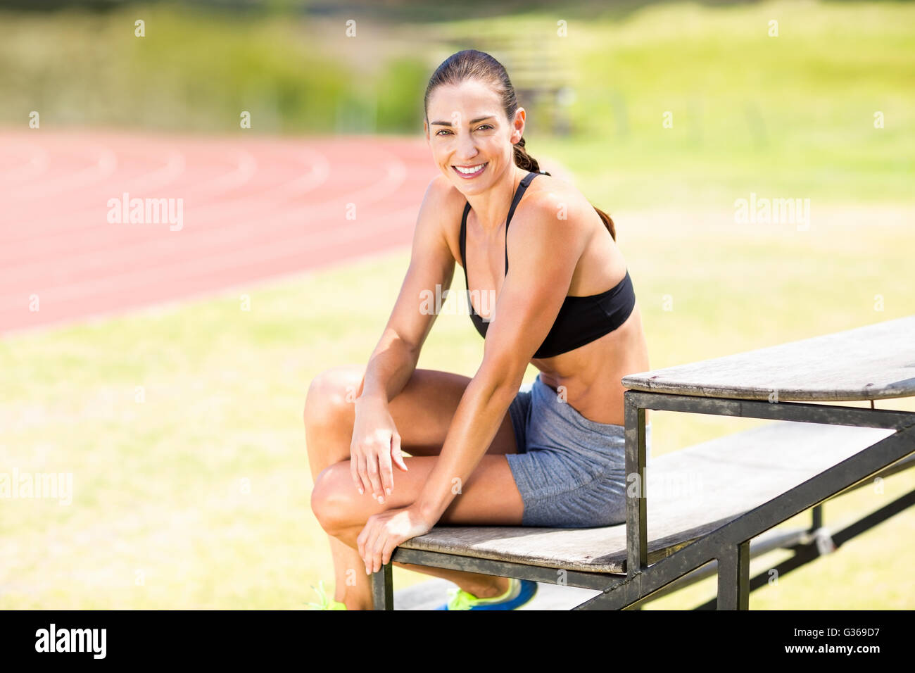Ritratto di felice atleta donna seduta su supporto Foto Stock