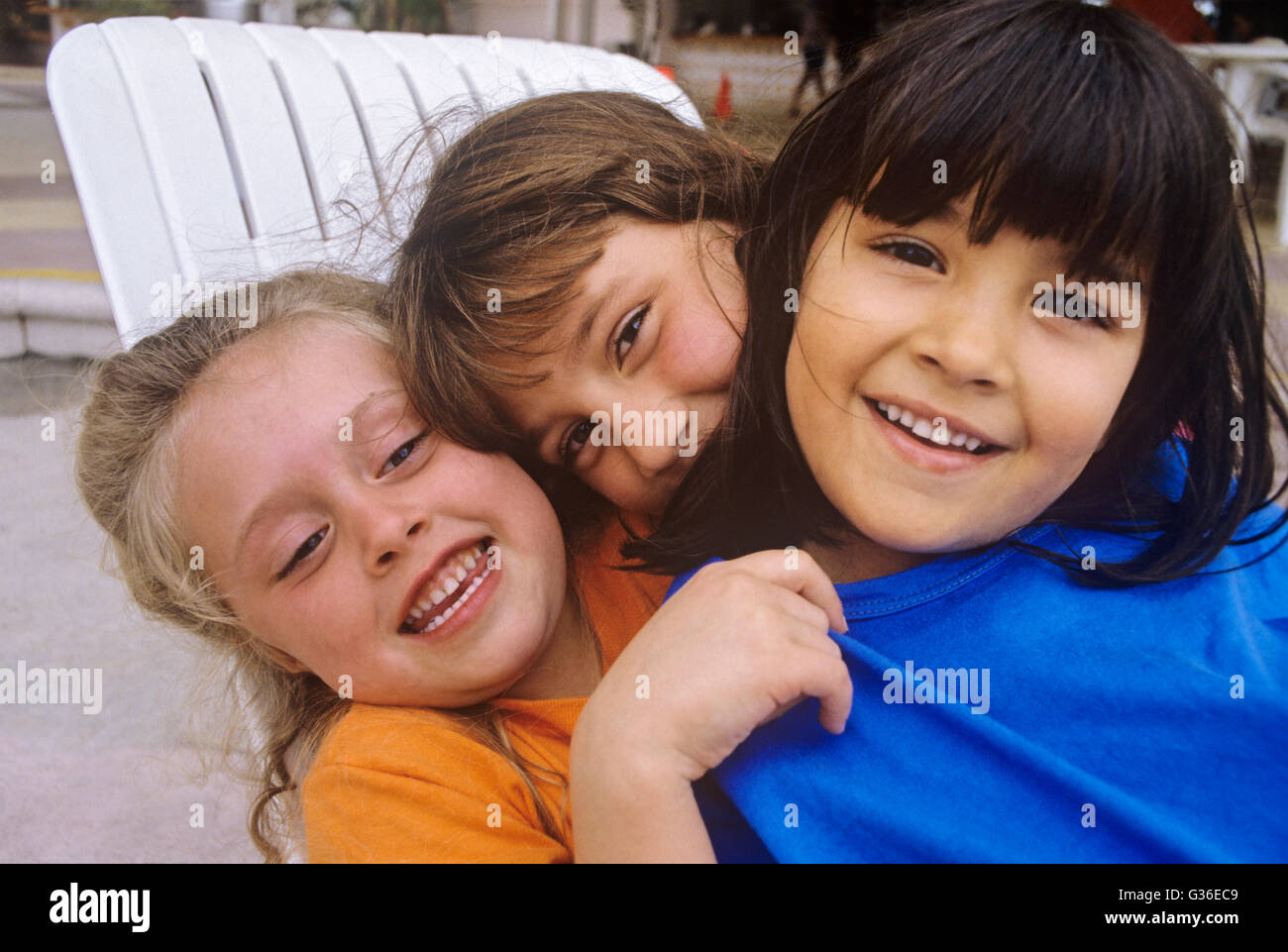 3 bambini abbracciando multi-gruppo razziale Foto Stock