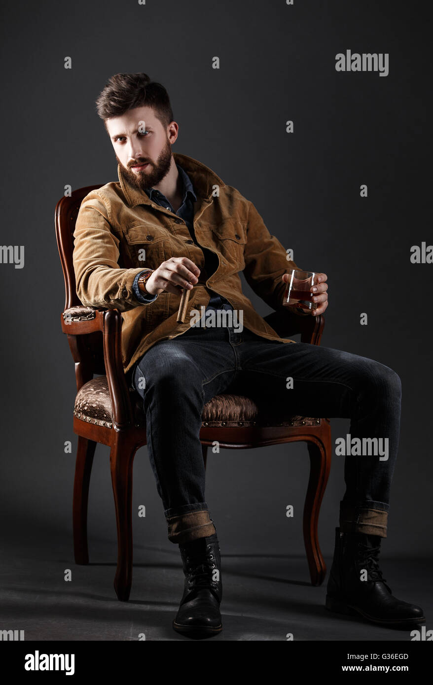 Ritratto di grave uomo barbuto con sigaro e whisky Foto Stock