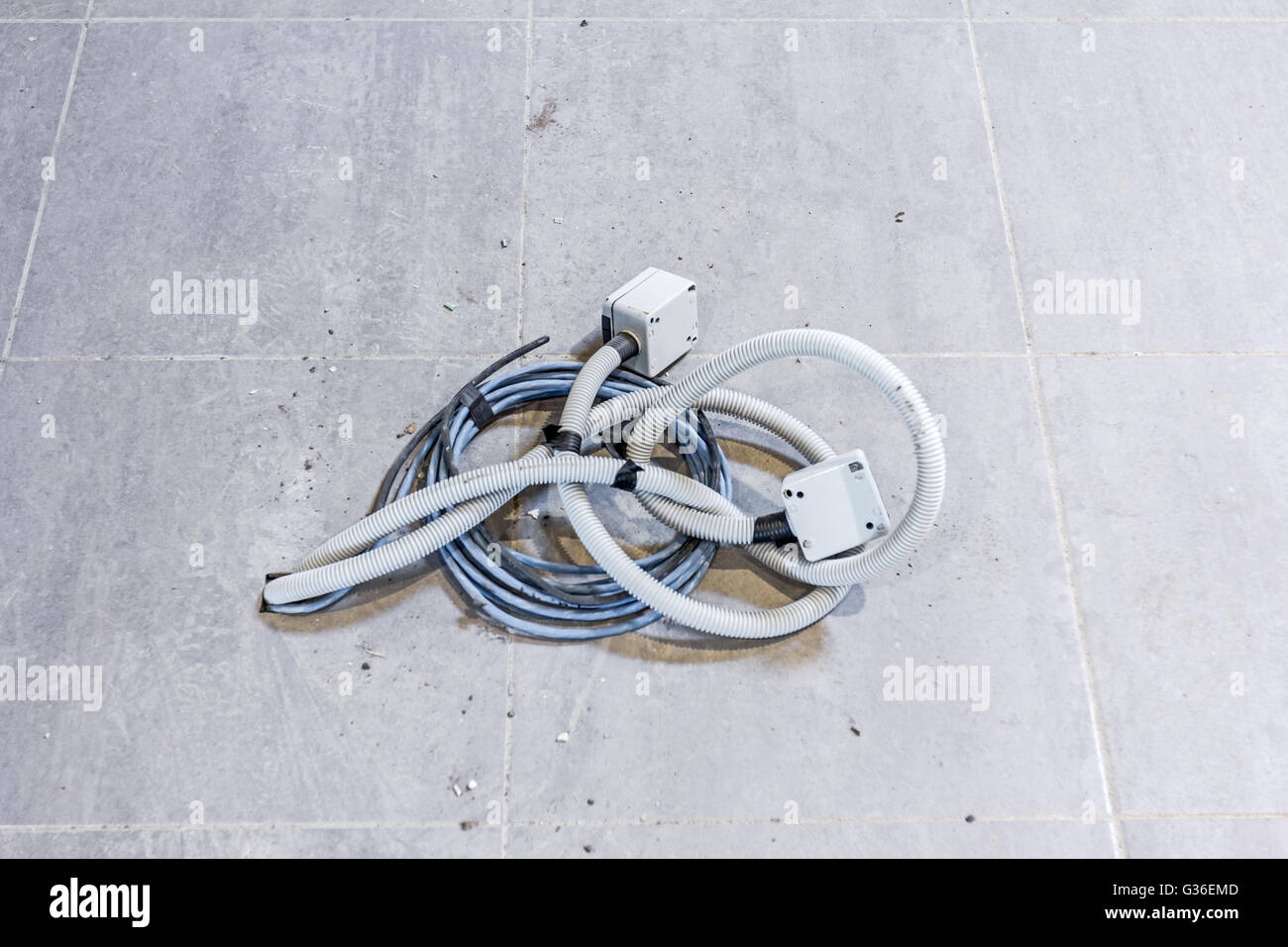Mazzetto di vari cavi elettrici sono venuta fuori dal pavimento piastrellato. Foto Stock