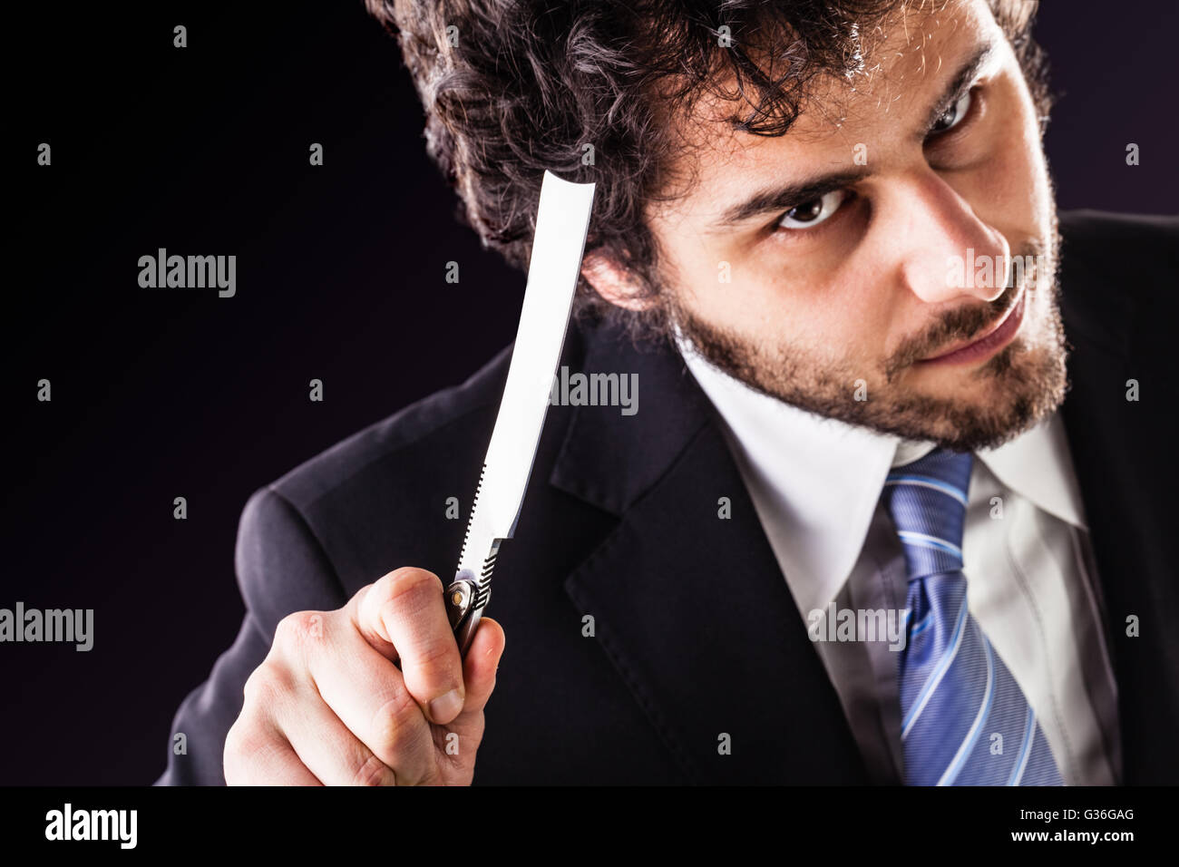 Un imprenditore bello indossare una tuta e un tirante tenendo un grosso taglio-gola rasoio Foto Stock