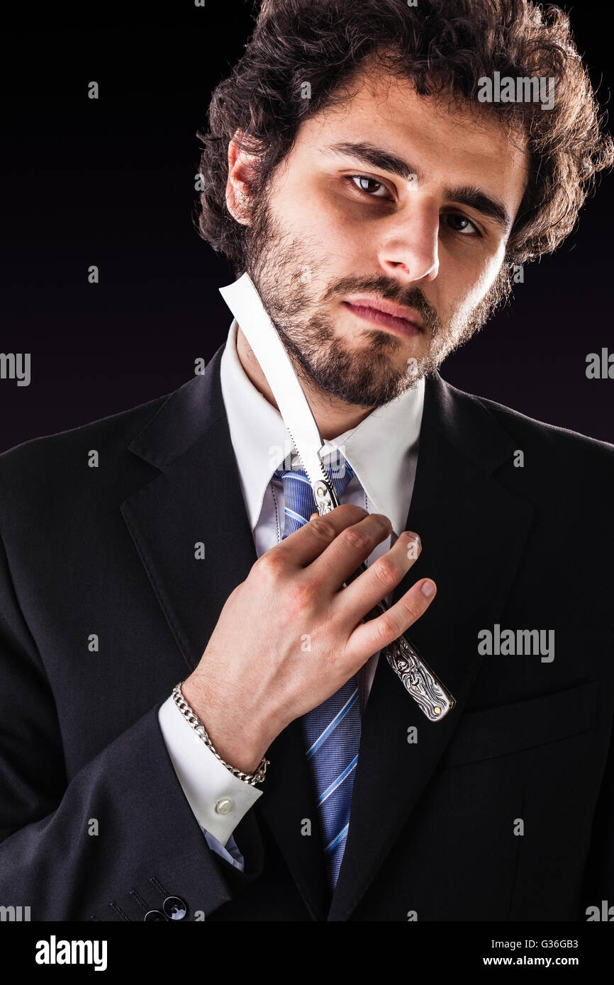 Un imprenditore bello indossare una tuta e un tirante tenendo un grosso taglio-gola rasoio Foto Stock