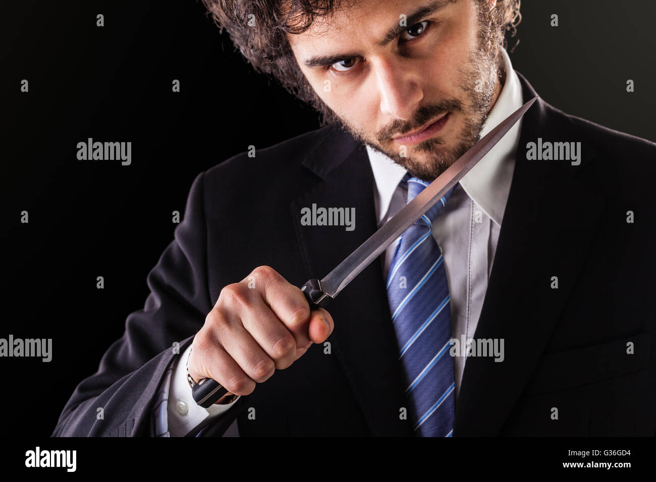 Un imprenditore bello indossare una tuta e un tirante tenendo un grosso coltello da cucina Foto Stock