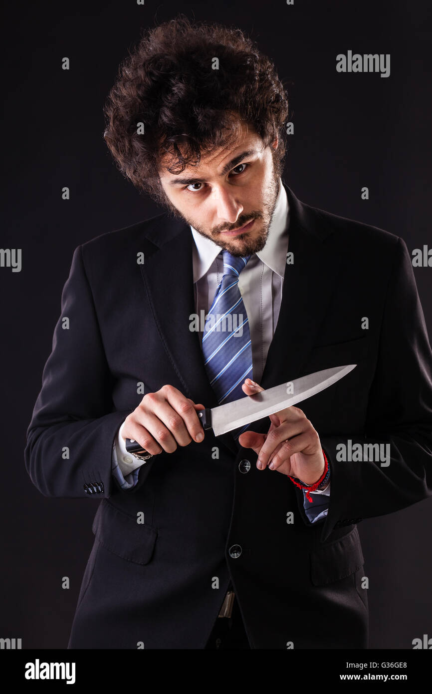 Un imprenditore bello indossare una tuta e un tirante tenendo un grosso coltello da cucina Foto Stock