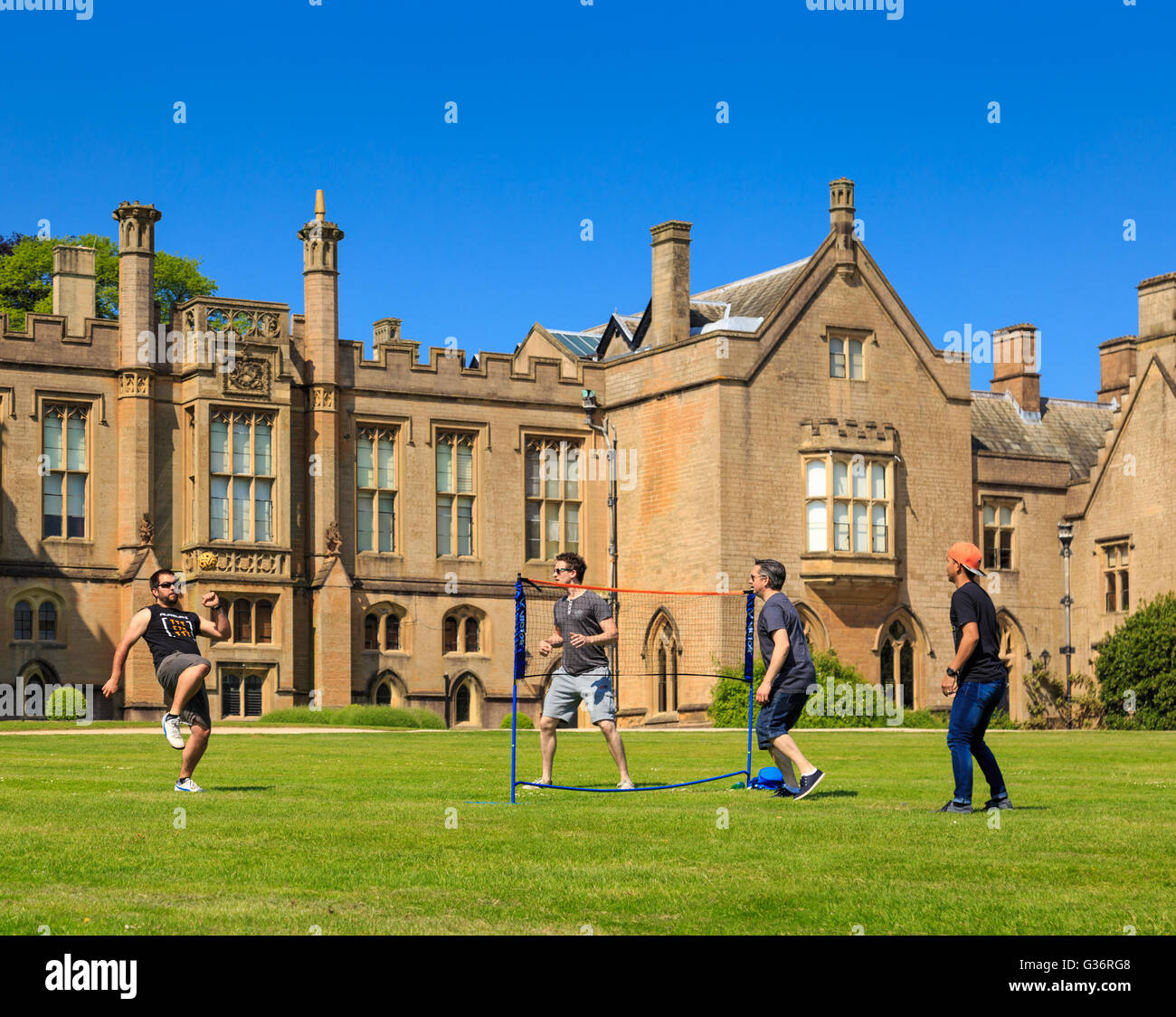 Un gruppo di giovani uomini giocando sepak takraw (kick pallavolo) sul prato. a Newstead Abbey, nottinghamsh Foto Stock