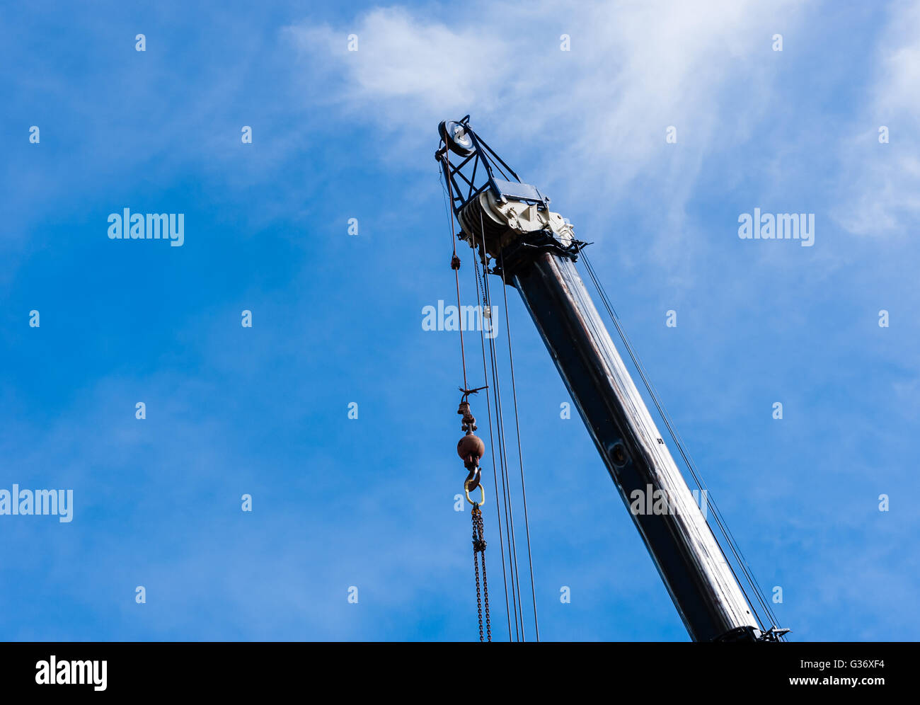 In alto di grandi pesanti gru industriali estesa nel cielo, con le pulegge e i cavi che pendono dalla parte superiore con peso e catene. Foto Stock