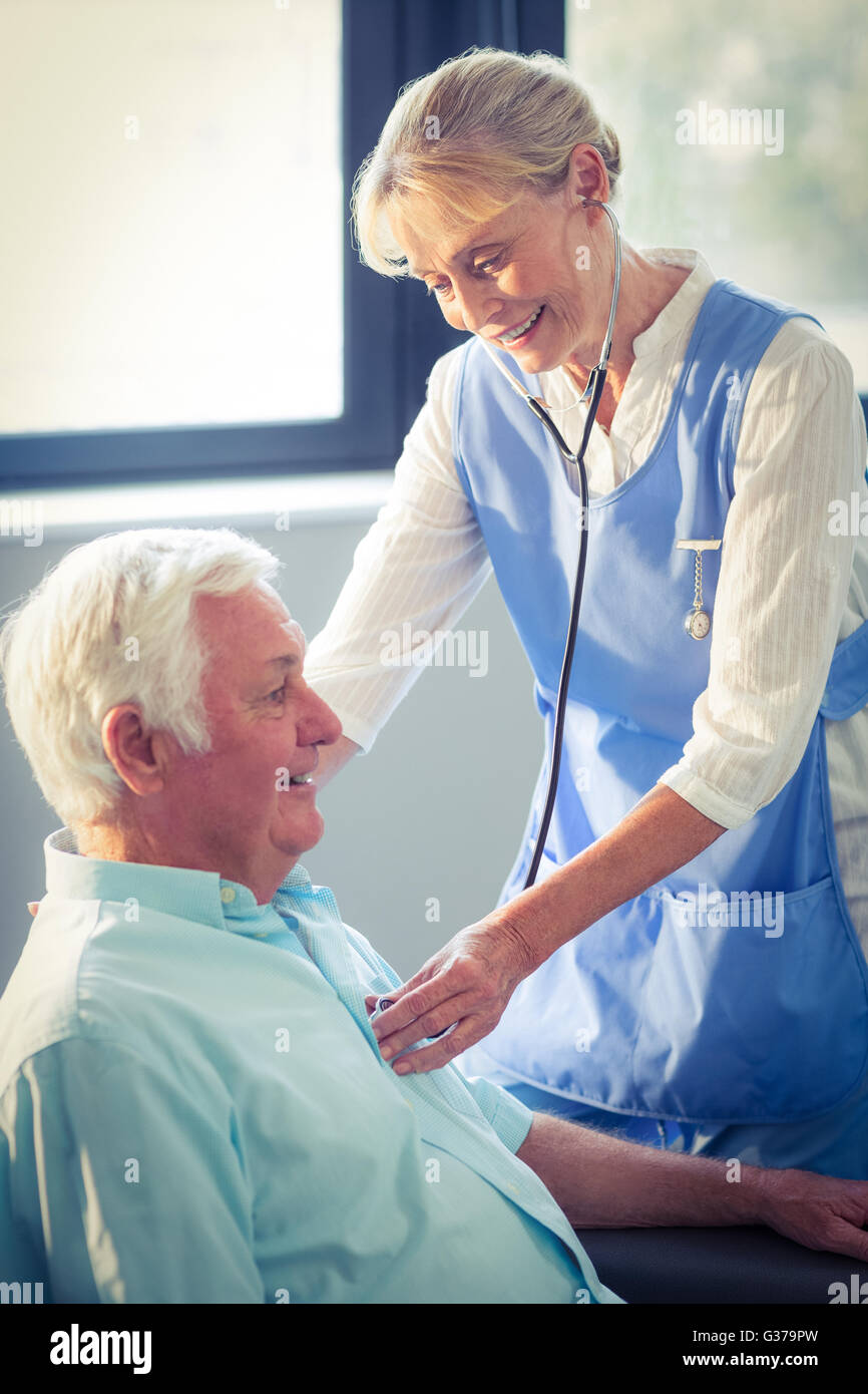 Medico donna controllo battito del cuore dell uomo senior Foto Stock