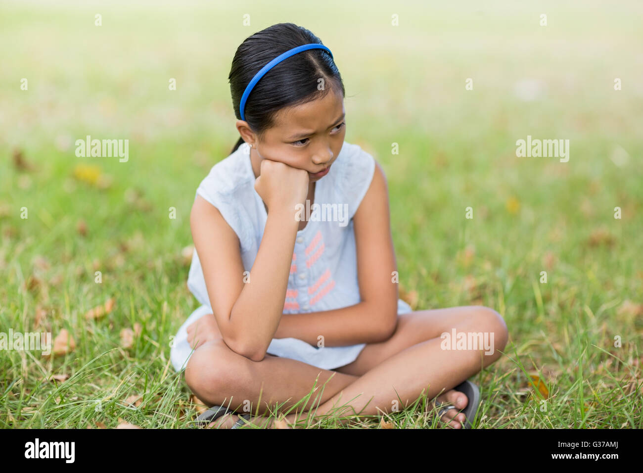 Sconvolto ragazza seduta sull'erba Foto Stock