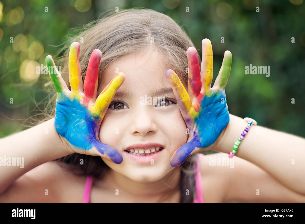 Sorridente Bambina guardando la fotocamera e mostrando il suo dipinto le mani Foto Stock