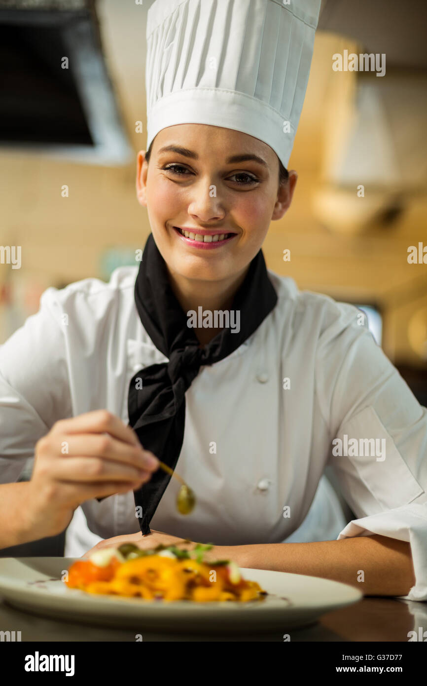 Felice capo chef guarnire piatti di pasta con olive Foto Stock