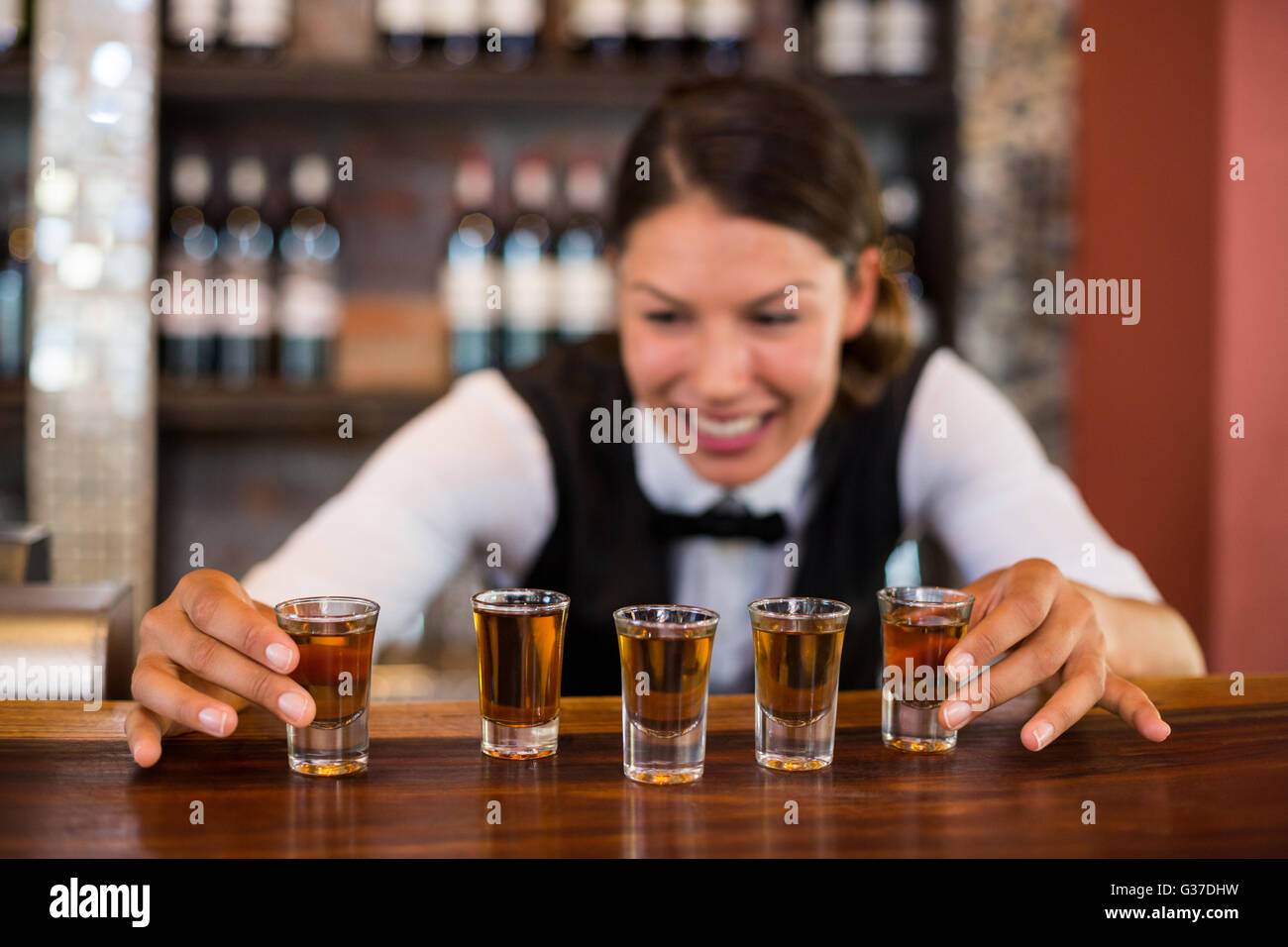 Barista immissione bicchierini sul bancone bar Foto Stock