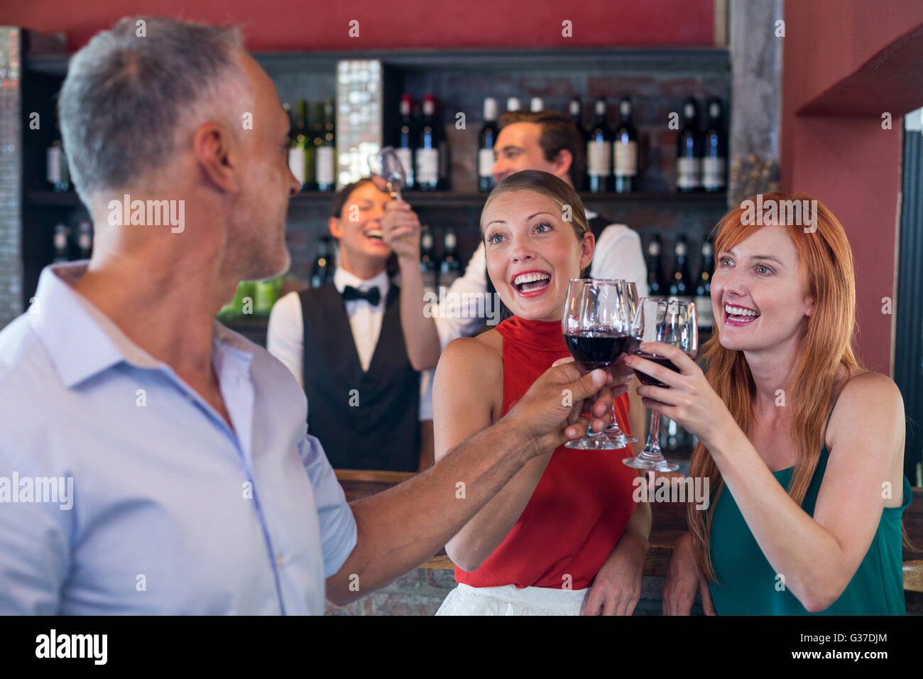 Amici bevendo un bicchiere di vino rosso in un bar Foto Stock