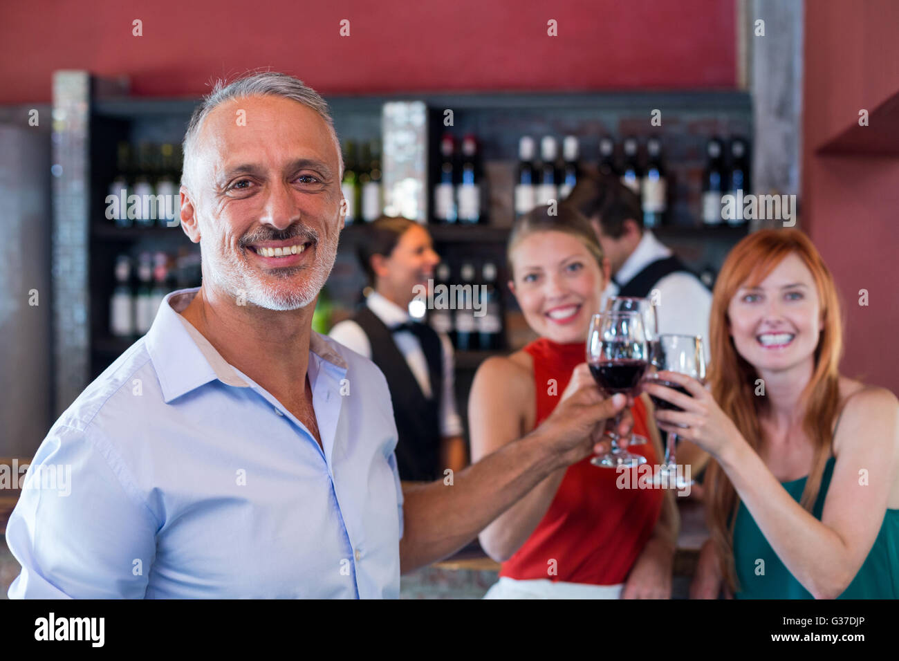 Ritratto di amici bevendo un bicchiere di vino rosso in un bar Foto Stock