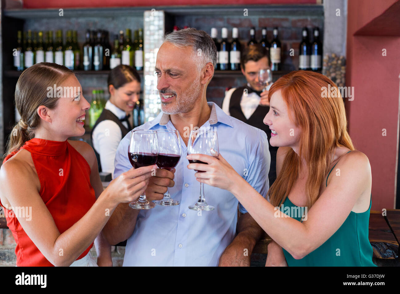 Amici bevendo un bicchiere di vino rosso in un bar Foto Stock