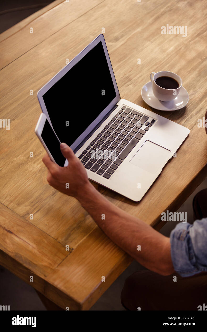 Immagine ritagliata di laptop e uomo utilizza lo smartphone Foto Stock