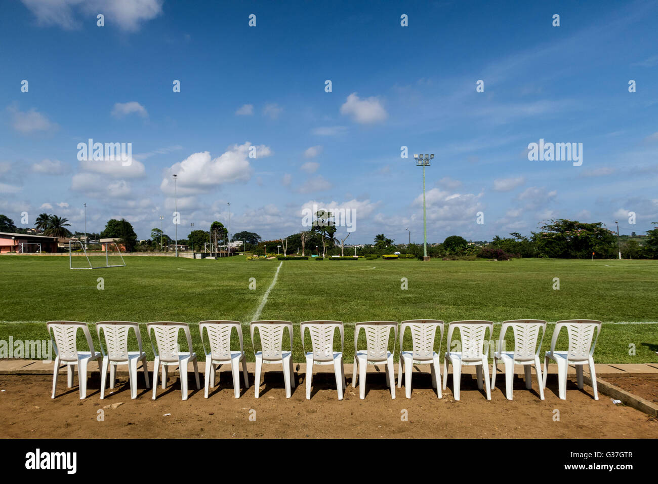 Fila di spettatore sedie allineate accanto a una pratica di massa di calcio ad Abidjan, in Costa d Avorio. Foto Stock