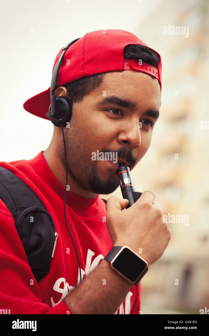 Ritratto di black boy utilizzando i moderni e-cig dispositivo vaporizzatore per il fumo liquido di glicerina tabacco con gusto. Gadget popolare tra i giovani e che desiderano migliorare la salute e a smettere di fumare Foto Stock