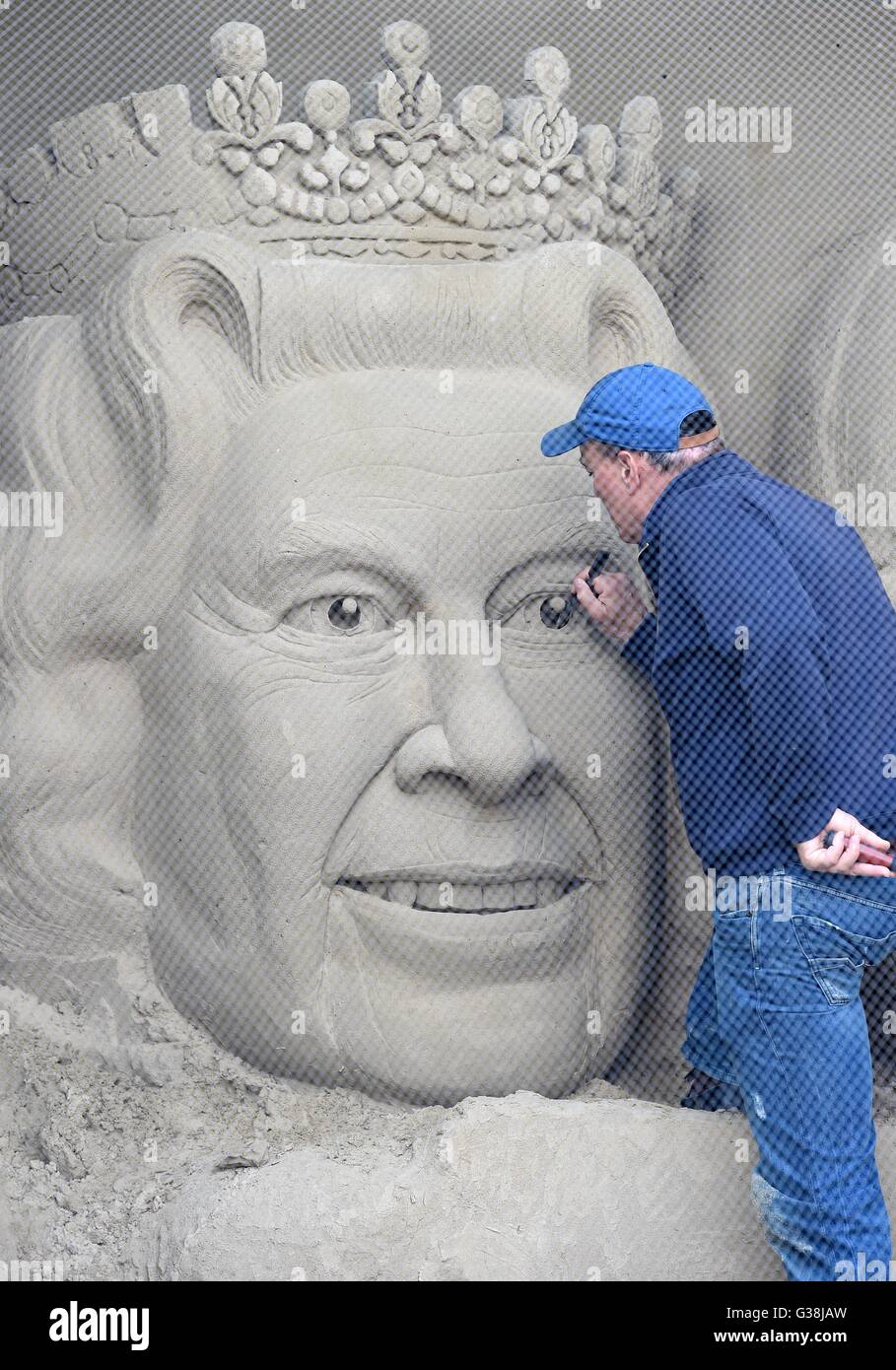 Scultore di sabbia 'Marca Anderson' mette i tocchi di rifinitura per la scultura della regina Elisabetta, Dorset, Regno Unito Foto Stock