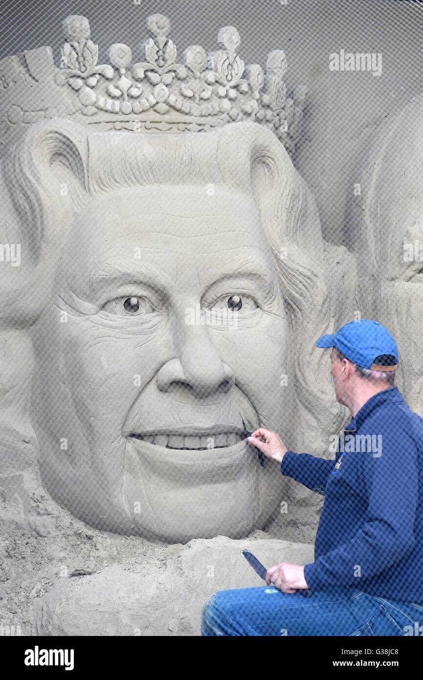 Scultore di sabbia 'Marca Anderson' mette i tocchi di rifinitura per la scultura della regina Elisabetta, Dorset, Regno Unito Foto Stock