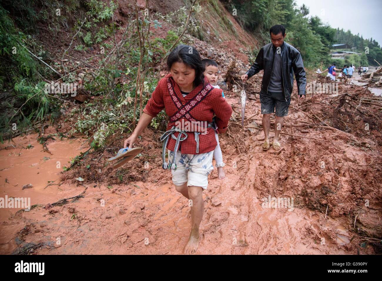 Rongjiang, della Cina di Guizhou. Decimo Giugno, 2016. Una donna che porta un bambino cammina duro su una strada fangosa in Zaima township di Rongjiang County, a sud-ovest della Cina di Guizhou, 10 giugno 2016. Tre persone rimangono mancante dopo la pioggia-innescato inondazioni nella provincia di Guizhou. Dalle 8 a.m. Giovedì alle 8 del mattino Venerdì, heavy rain ha colpito più di 100 township di Guizhou, Credito: Liu Xu/Xinhua/Alamy Live News Foto Stock