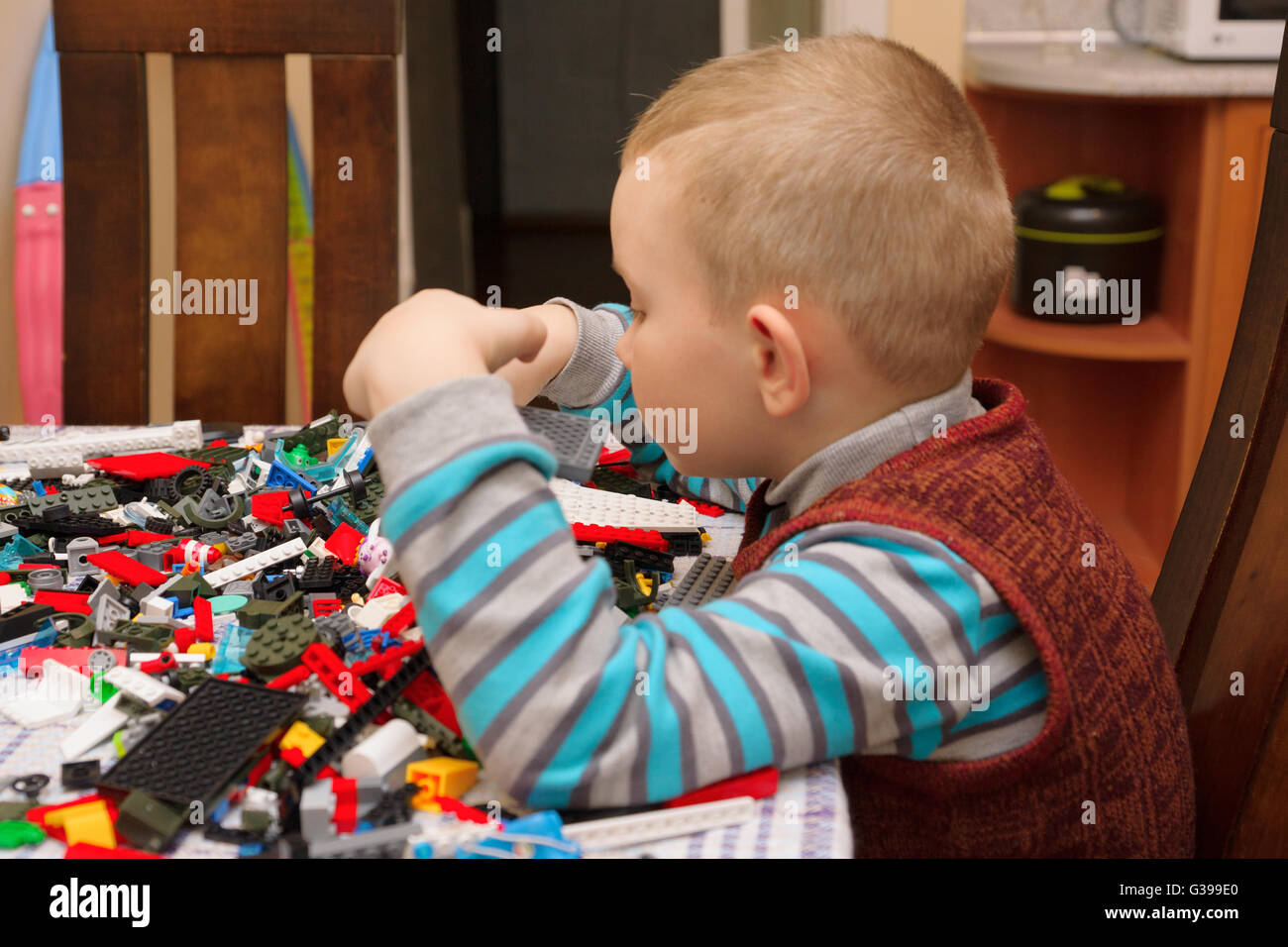 Ragazzo seduto al tavolo e cosa che crea una struttura complessa Foto Stock
