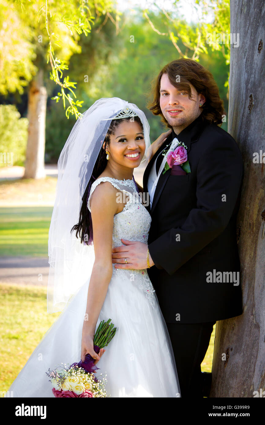 Sposa e lo Sposo posare per un matrimonio post ritratto da un albero. Foto Stock