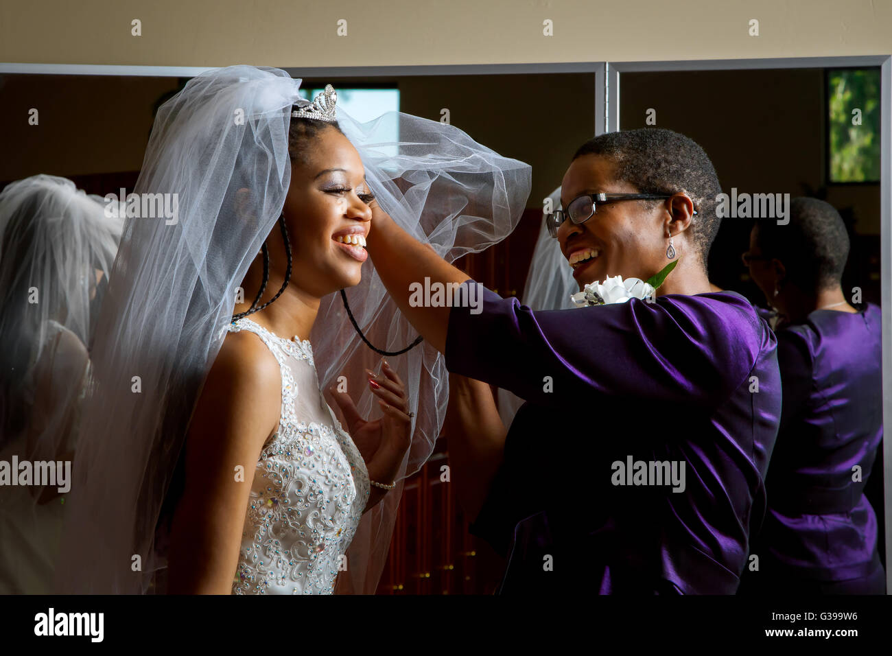 Madre della sposa regola la figlia della velo sul suo giorno di nozze. Bella, americano africano donne, sorridente. Foto Stock