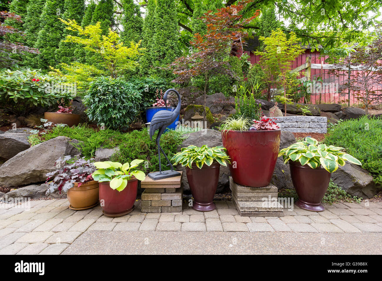 Casa giardino con cortile e hardscape softscape con piante e alberi lastricatori pietre vasi colorati contenitori nel paesaggio Foto Stock