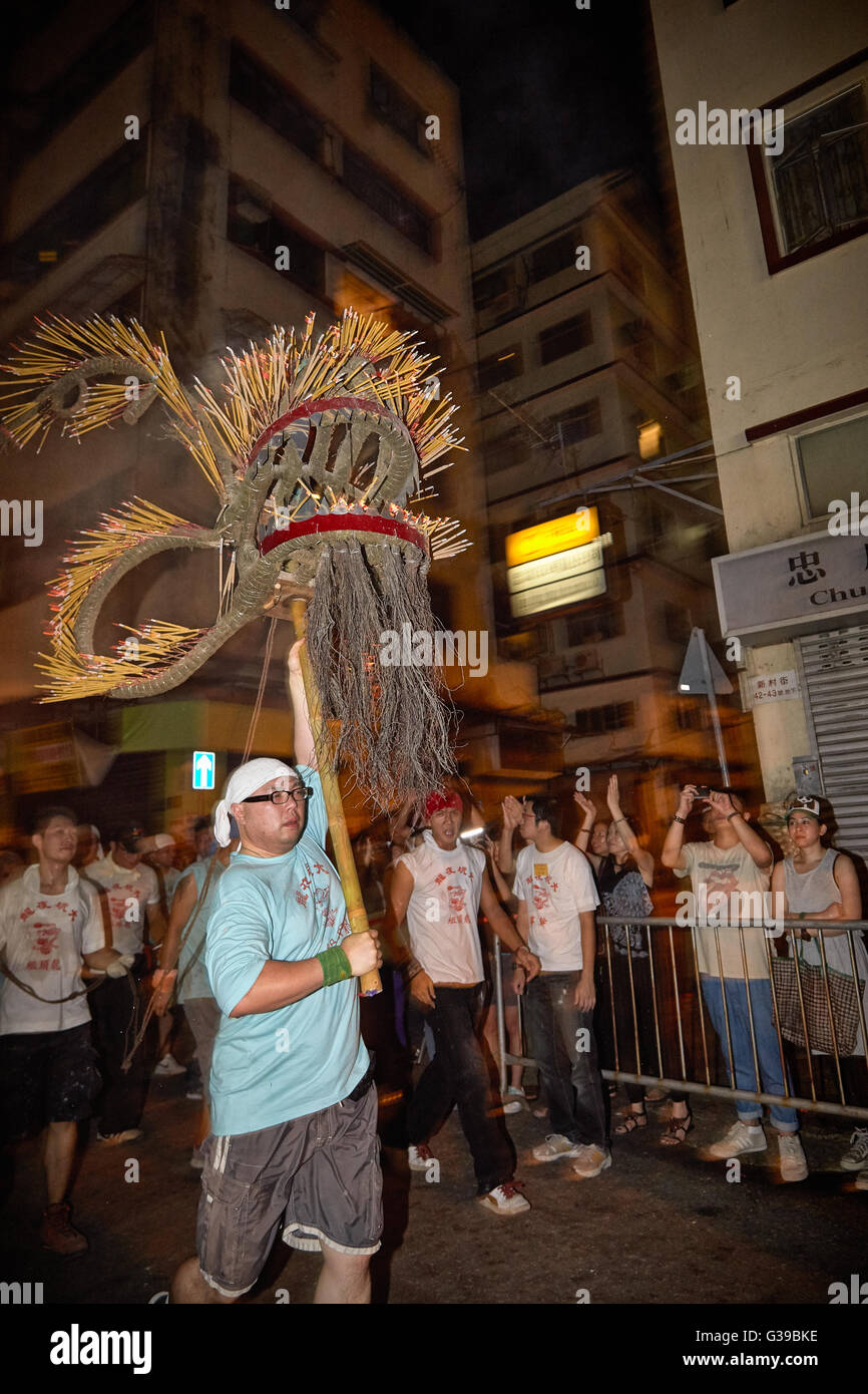 Un carrier di paranchi aloft la tremante e fiery incenso laden testa dell'ormai famoso Fire Dragon Dance in Tai Hang, Hong Kong. Foto Stock