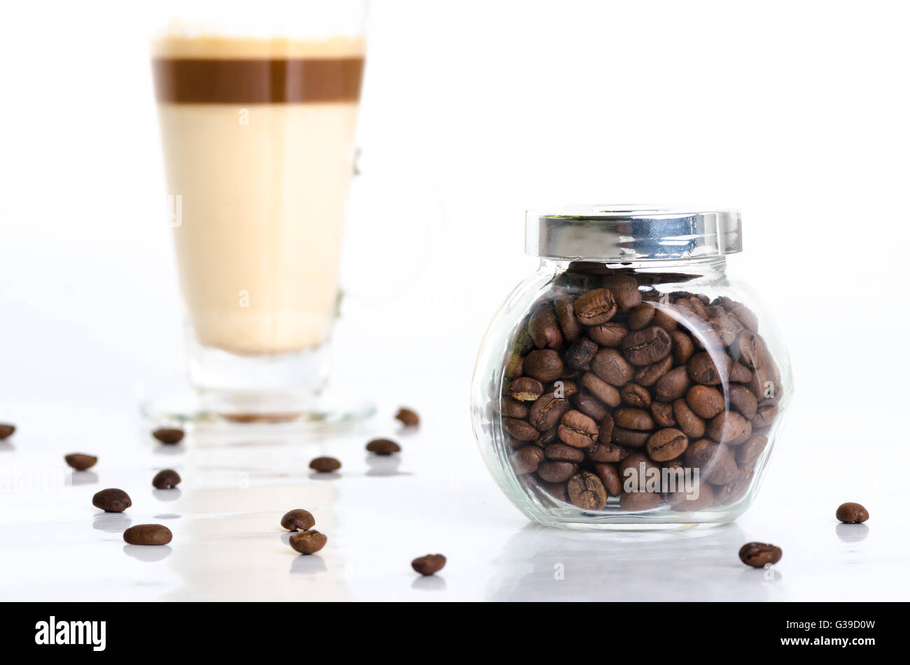 Vasetto trasparente con i chicchi di caffè e latte macchiato isolati su sfondo bianco Foto Stock