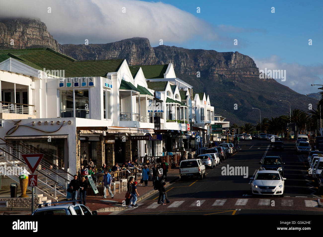 Scena di strada a Victoria Road Camps Bay Beach, con tabella montagne sullo sfondo di Città del Capo, Sud Africa Foto Stock