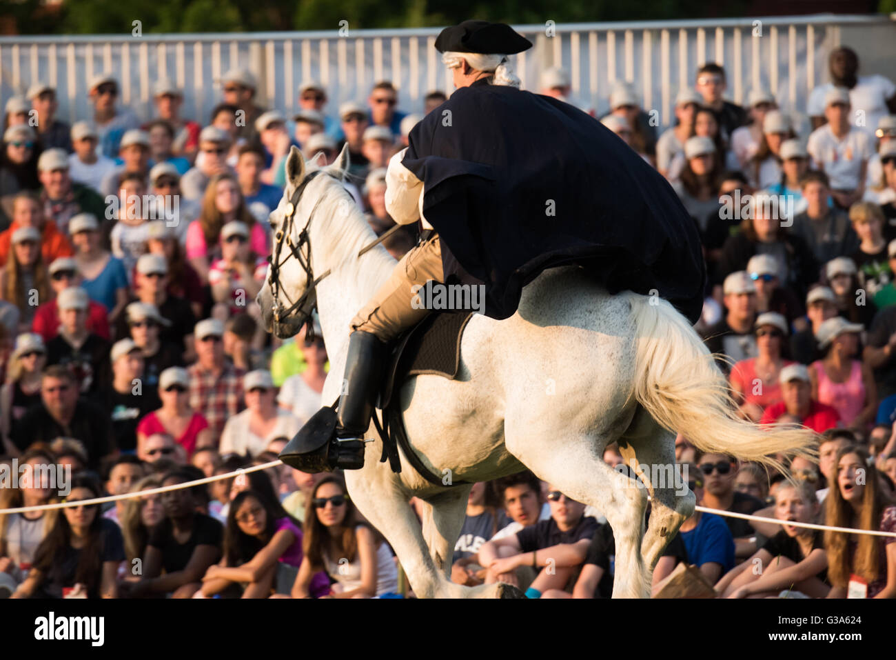 Spettacolo del tatuaggio del crepuscolo dell'esercito STATUNITENSE Arlington Virginia // ARLINGTON, Virginia - Un artista a cavallo ritrae la storica corsa di Paul Revere durante lo spettacolo del tatuaggio del crepuscolo dell'esercito statunitense. Questo concorso militare pubblico e gratuito si tiene presso la base congiunta di Myer-Henderson Hall. L'evento mostra la precisione e la disciplina delle unità cerimoniali dell'esercito degli Stati Uniti. Queste unità includono il 3rd U.S. Infantry Regiment (The Old Guard) e la U.S. Army Band Pershing's Own. Il Twilight Tattoo è una tradizione che celebra la storia e l'eccellenza militare. Foto Stock