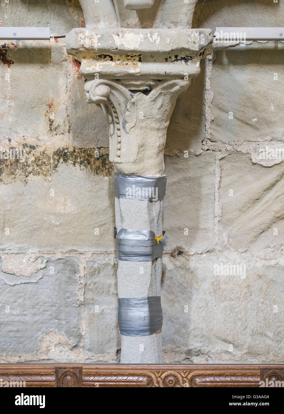 Storico in stile gotico pilastri in pietra con crepe e fessure, provvisoriamente fissato con nastro adesivo telato, sono in attesa di restauro. Foto Stock