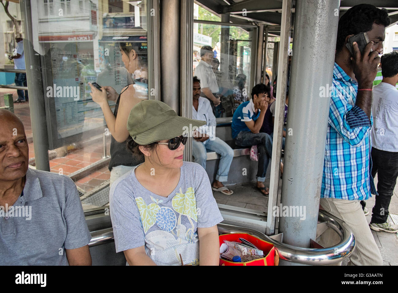 Pendolari aspettare ad una fermata degli autobus in Serangoon Road in Little India, Singapore Foto Stock