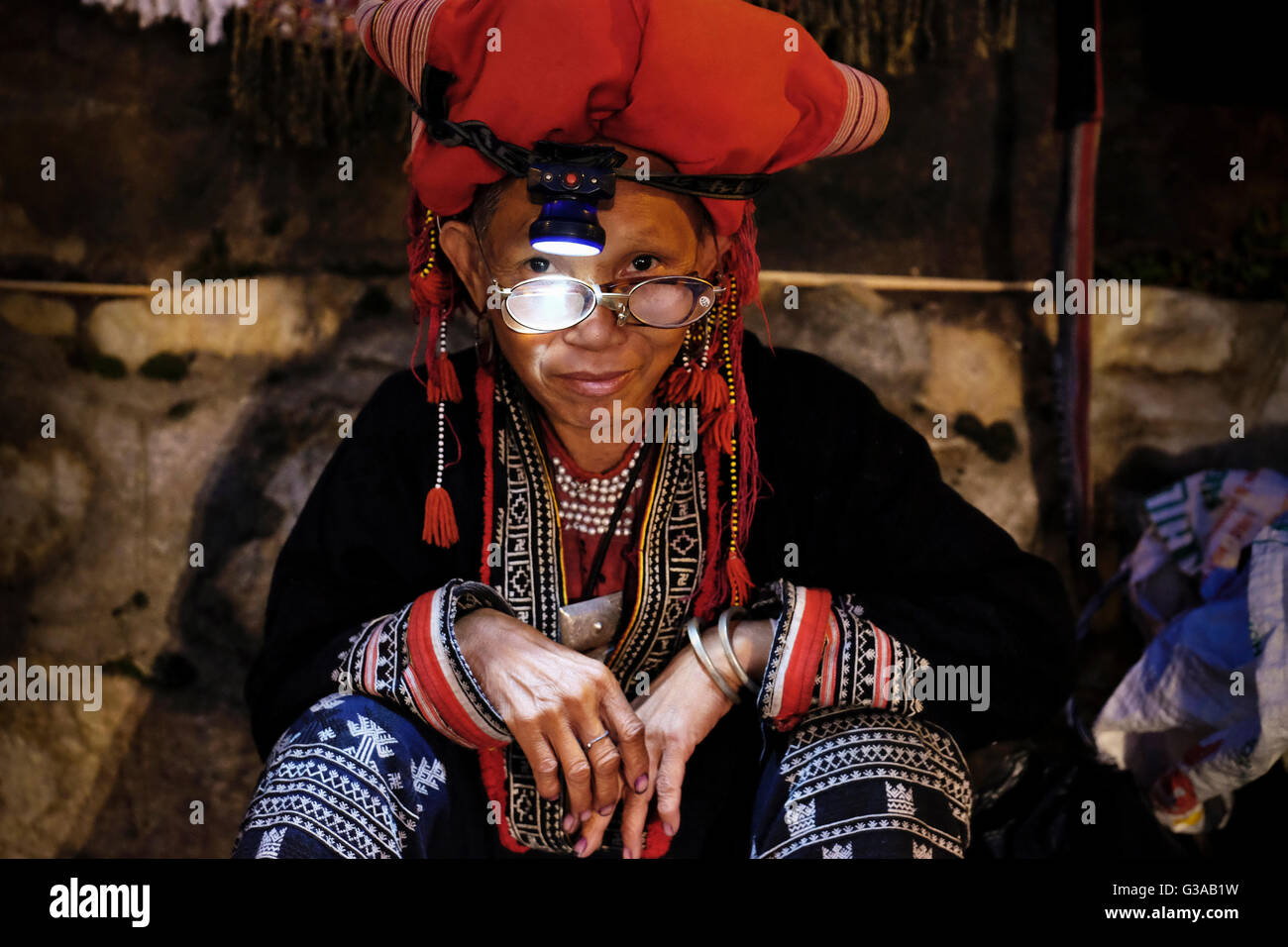 Un centro di età compresa tra i Red Dao donna tribale vende artigianato in una notte di strada del mercato di Sapa, Lao Cai Provincia, Vietnam Foto Stock