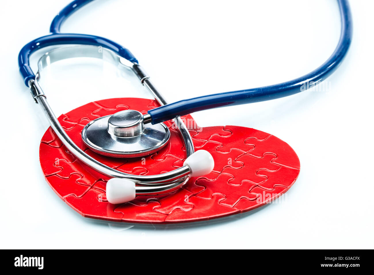 Rosso cuore puzzle con uno stetoscopio isolati su sfondo bianco, healthcare Foto Stock