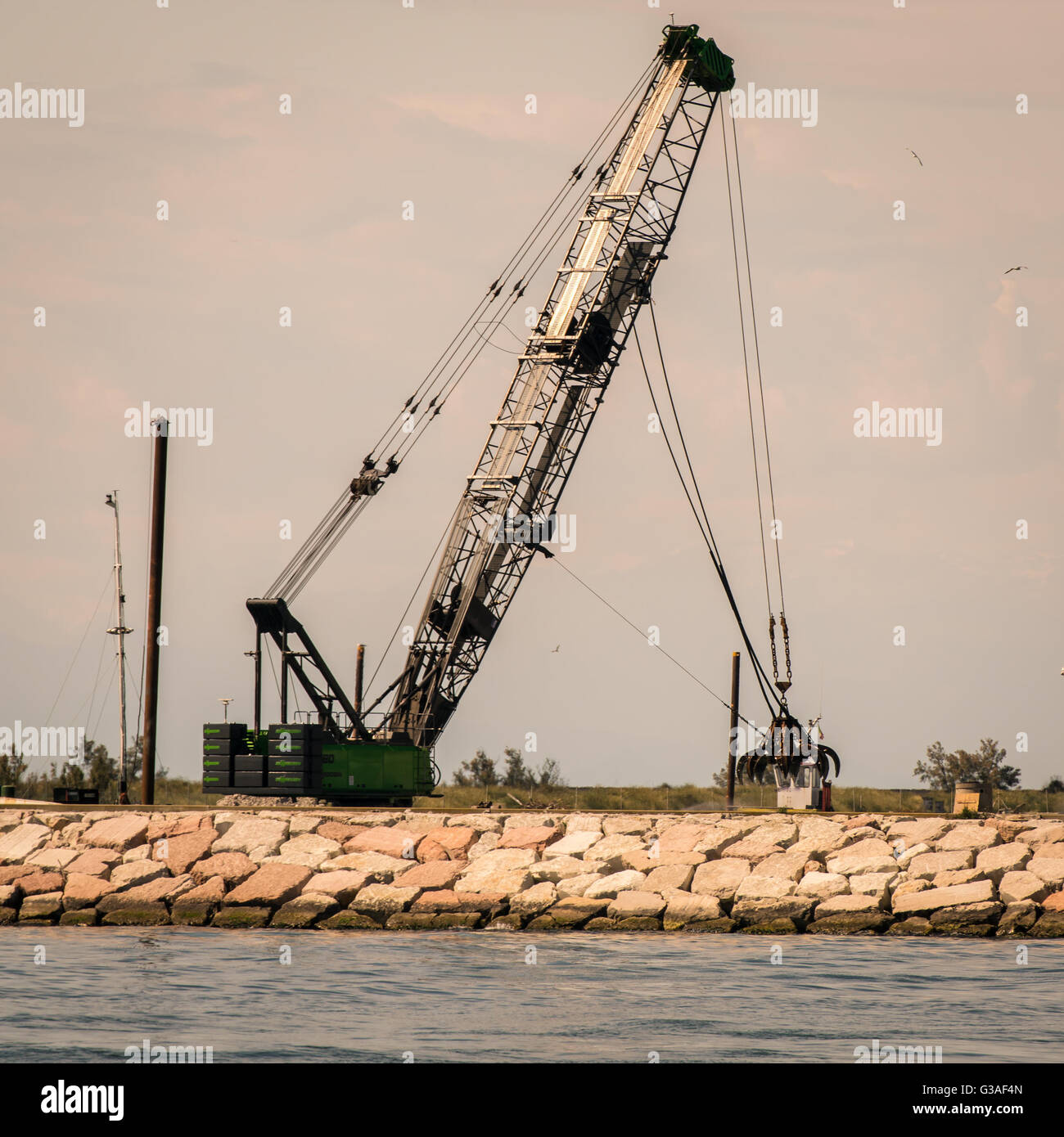 Afferrare la gru in azione per costruire un seawall. Foto Stock
