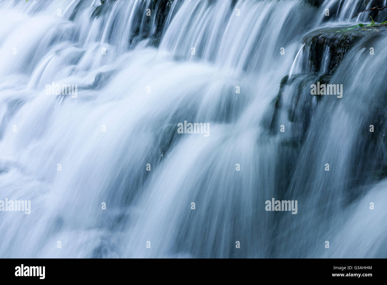 Acqua a cascata su uno stramazzo con motion blur. Tumbling Weir sul fiume Yeo a Wrington, North Somerset, Inghilterra. Foto Stock