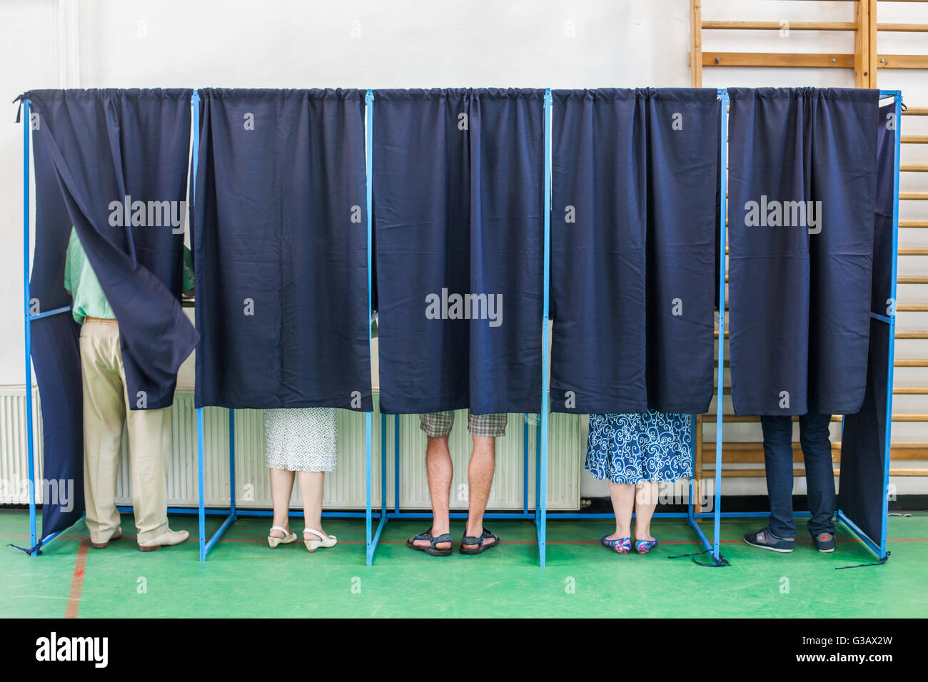 Immagine a colori di alcune persone voto in alcune cabine di polling in corrispondenza di una stazione di voto. Foto Stock