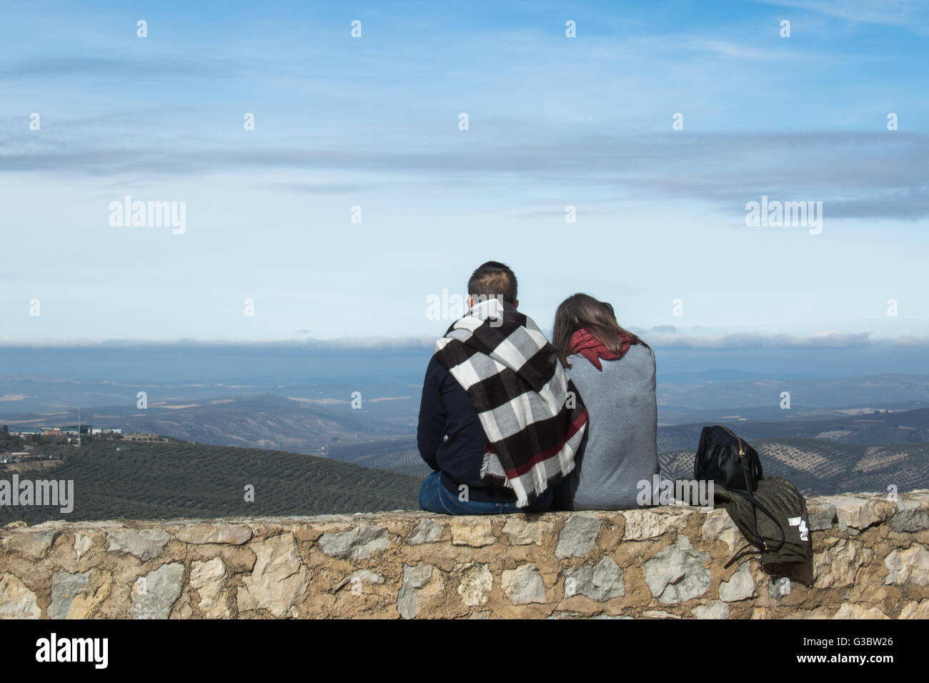 Coppia giovane seduto su una parete guardando in vista delle colline dal castello di Cazorla, Spagna Foto Stock