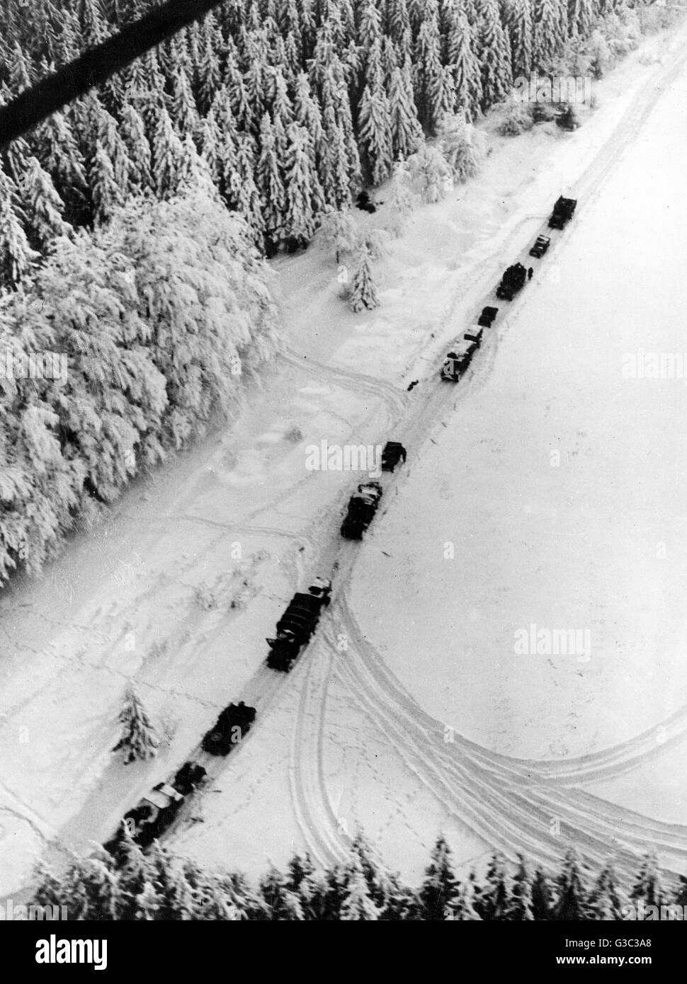 Una veduta aerea di trasporto in movimento colonna attraverso la neve nella foresta delle Ardenne, verso una batteria di artiglieria, durante la Battaglia di Bulge Data: 1944-1945 Foto Stock