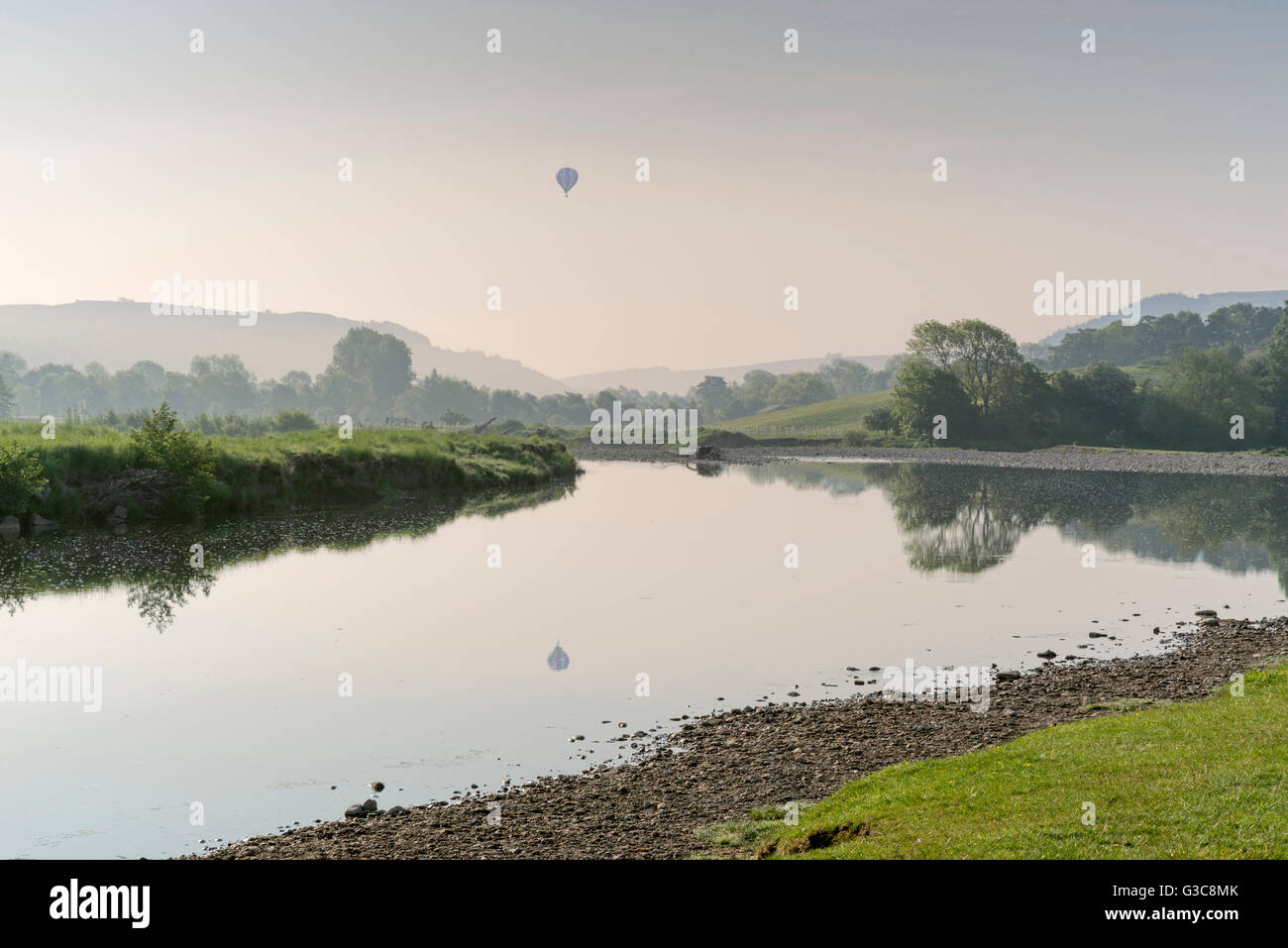 Prima luce a Reeth in Swaledale, Yorkshire Dales, e un pallone aerostatico sul fiume swale. Foto Stock