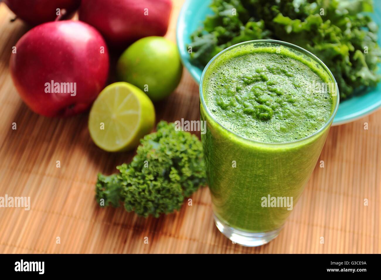 Un sano frullato verde con cavolo riccio, apple e lime fresco in un bicchiere Foto Stock