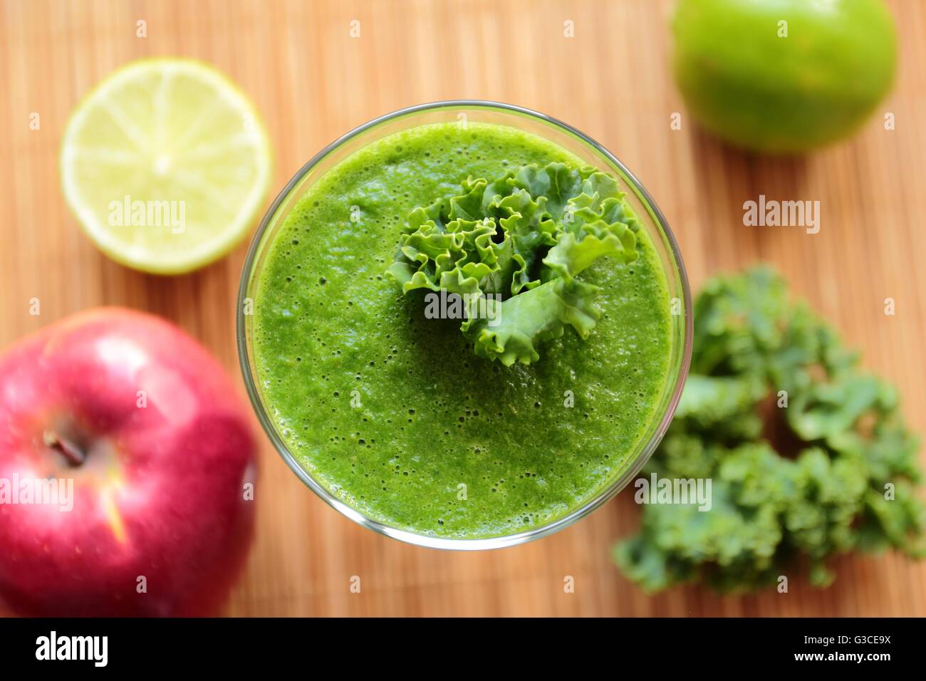 Al di sopra di visualizzare su una lastra di vetro con un sano frullato verde con kale, apple e calce Foto Stock