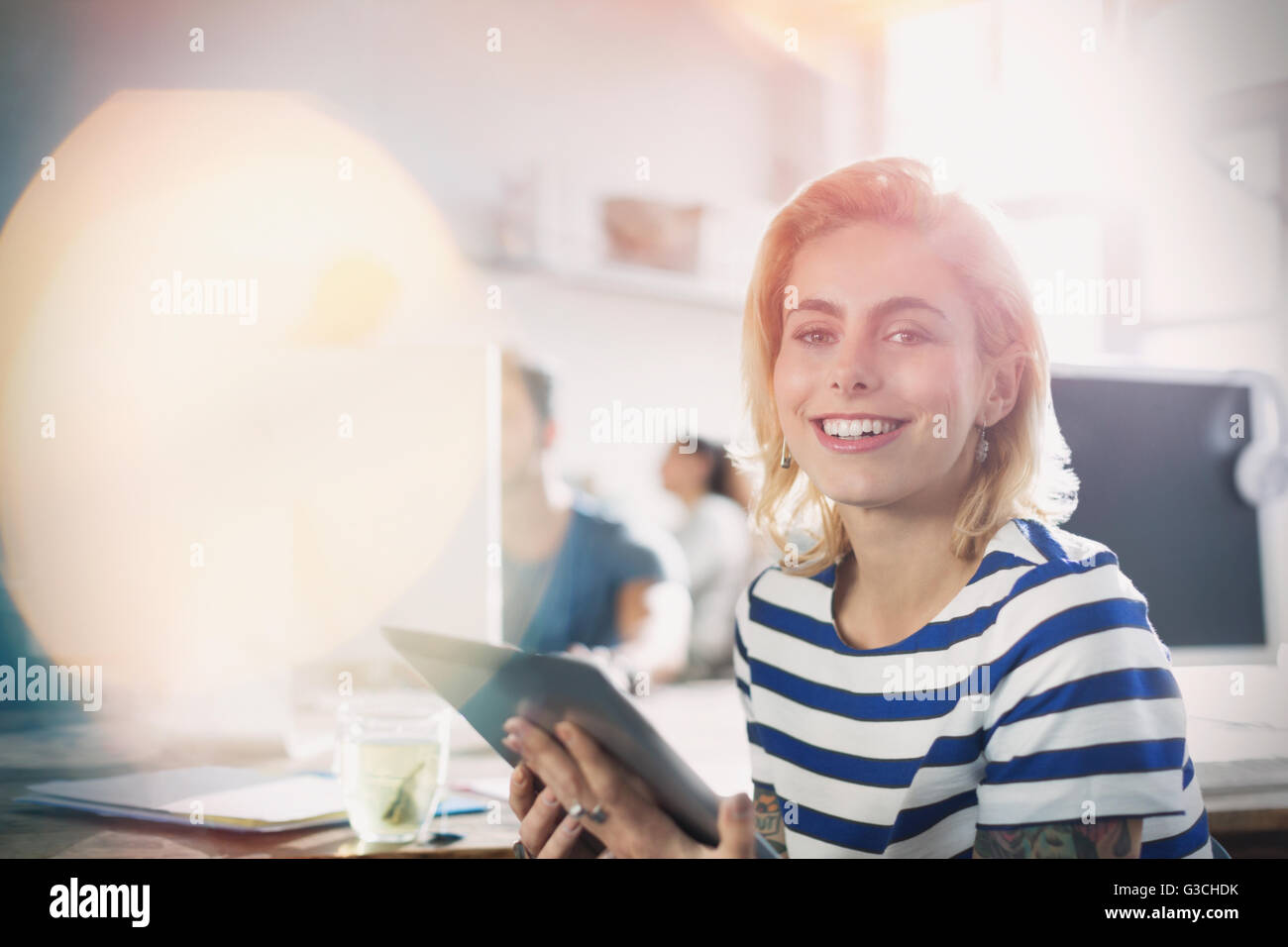 Ritratto sorridente giovane imprenditrice creativa con tavoletta digitale in ufficio Foto Stock